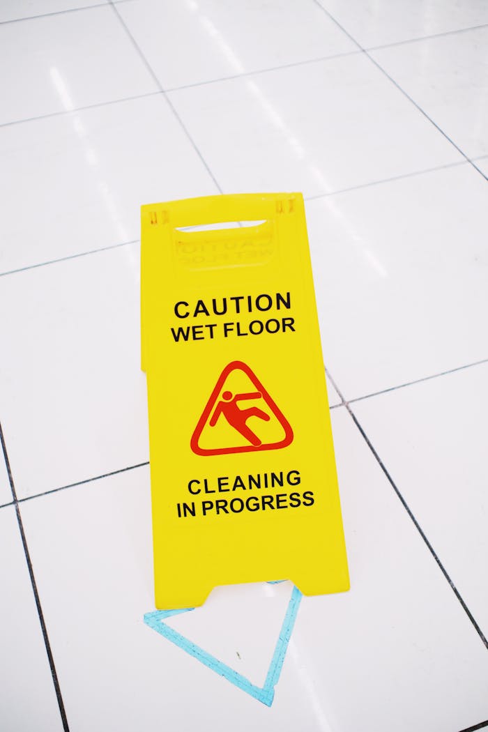 home-services-01 From above of plastic yellow sign with inscription Caution wet floor placed on clean white tiles